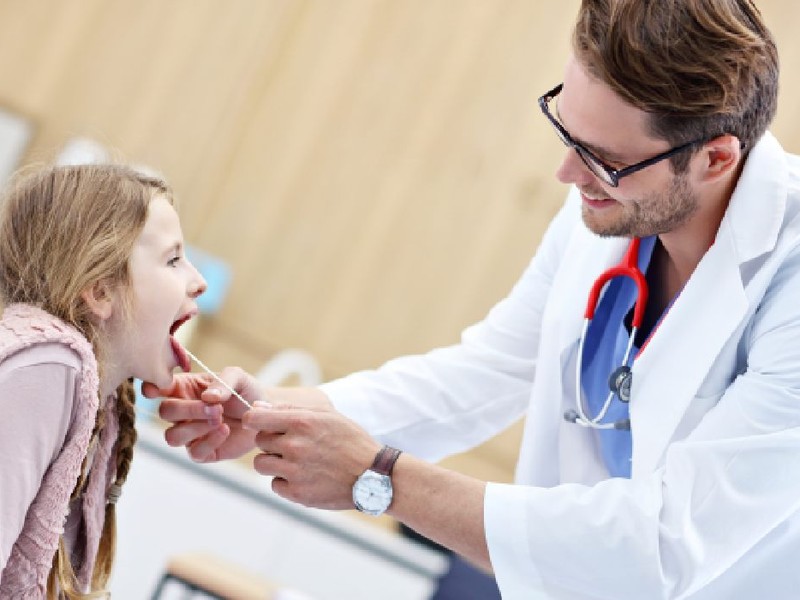 Medic  examinand un copil pentru suspiciune de streptococ beta hemolitic 