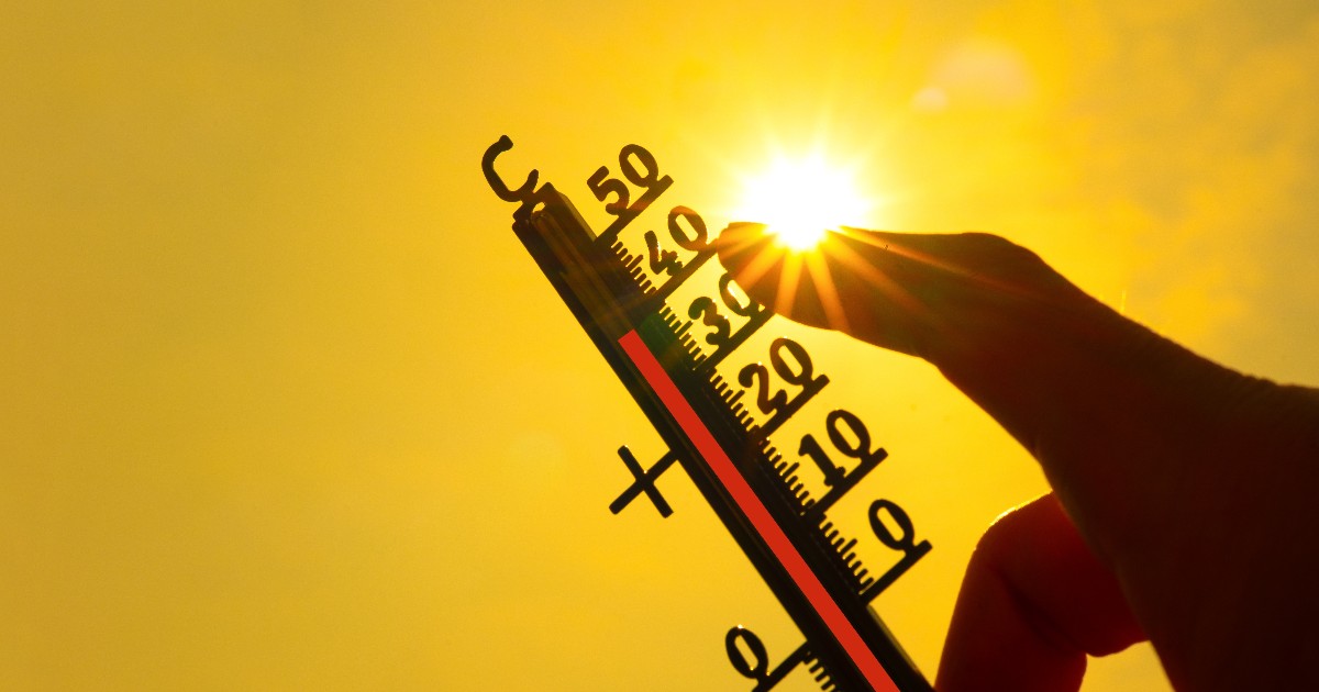 Imaginea prezintă o mână care ține un termometru orientat spre soarele puternic, indicând o temperatură ridicată de peste 35°C pe un fundal galben strălucitor.