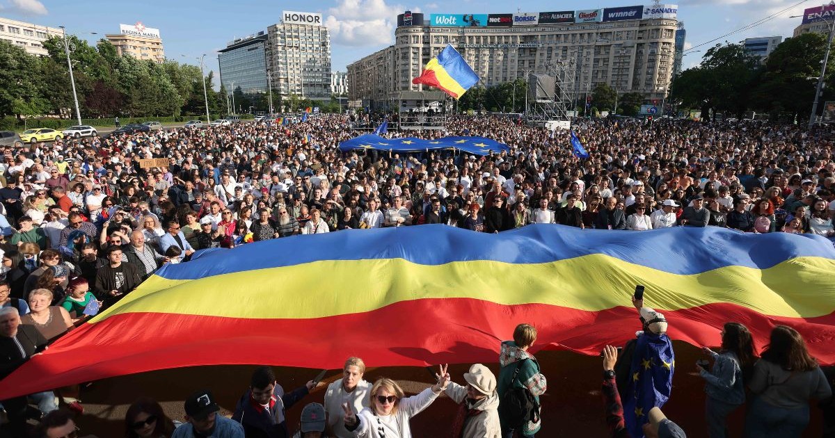 oameni prezenți la mitingul „România în Lumină” de duminică, 11 mai, 2025, țin deasupra lor un tricolor
