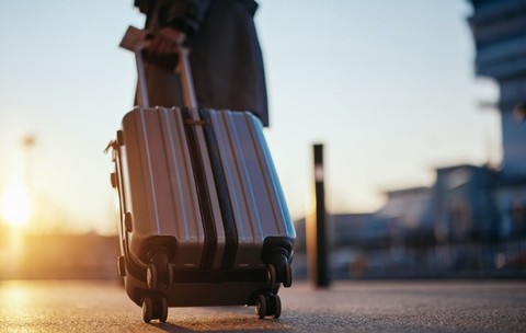 Călător cu valiză sosind la aeroport la răsăritul soarelui