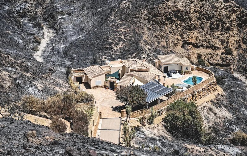 Casa rămasă intactă în mijlocul flăcărilor, pe un deal din Spania. Proprietarii, doi belgieni, au fugit când a luat foc vegetația dimprejur și au fost găsiți morți