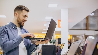 Bărbat care testează un laptop într-un magazin