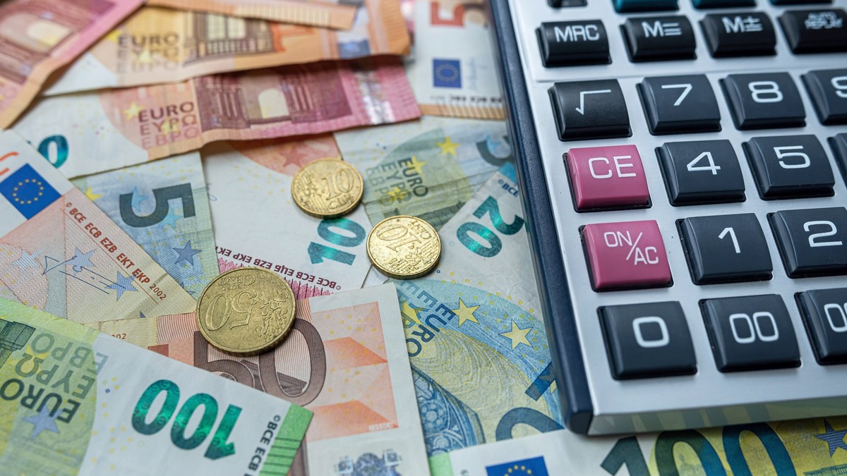 monede și bancnote de euro puse pe o suprafață, un calculator în partea dreaptă