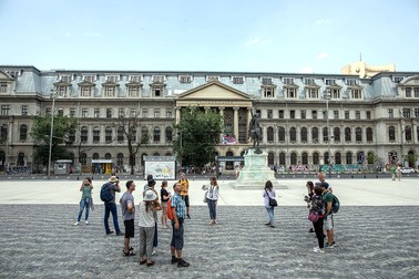 Turiștii admiră arhitectura clădirilor din Piața Universității
