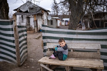 Eugen, 7 ani, stă pe băncuţa din faţa casei