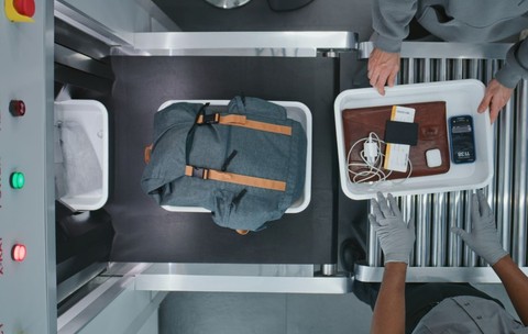 Vedere de sus asupra unor persoane diverse, pasageri care își așează obiectele personale în tăvi de plastic pentru procedurile de control pe banda transportoare cu scaner cu raze X. Punctul de control de securitate din aeroport înainte de îmbarcarea în avion.