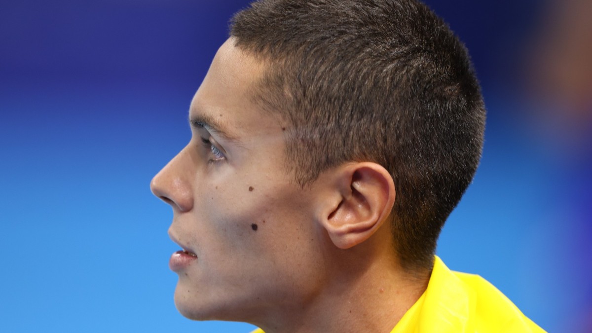 David Popovici, văzut din profil, cu steagul României pe umeri
