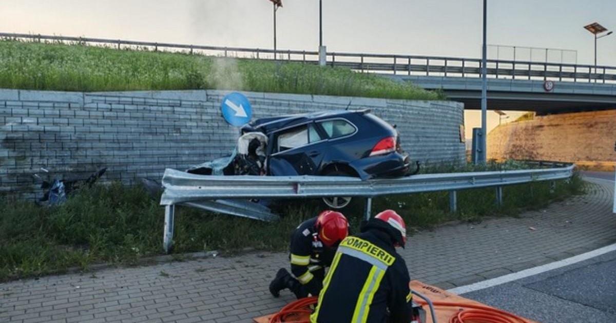 O mașină de culoare neagră, marca Volkswagen Passat tip break, distrusă după impactul cu peretele de beton de la Șcheia, și un pompier care strânge cleștii cu care a scos victima din mașina distrusă