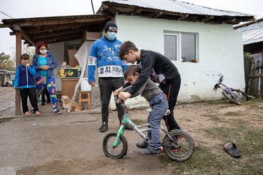 Vali, 12 ani, îl ajută pe fratele său Dani, 4 ani, să meargă pe bicicletă