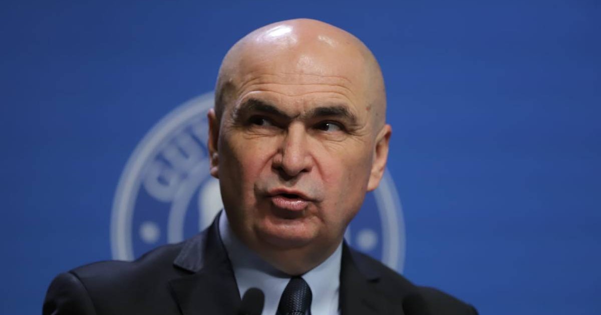 Premierul Ilie Bolojan, îmbrăcat într-un costum negru, este fotografiat portret, în timpul unei conferințe de presă la Palatul Victoria