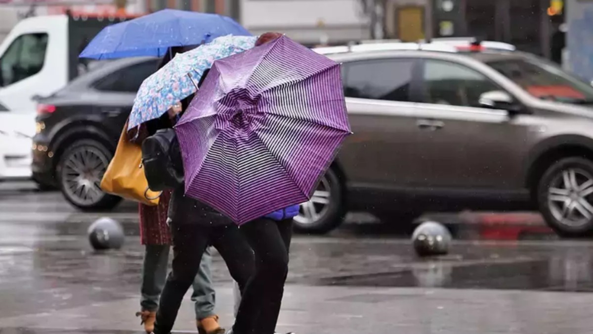 Imaginea ilustrează o zi ploioasă, în care mai mulți oameni merg pe stradă și au umbrele de diferite culori și modele, iar pe jos este apă
