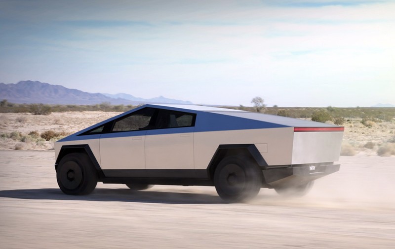 O camionetă Tesla Cybertruck depășește într-o cursă un Porsche, în timp ce tractează alt Porsche. Modelul va costa cu 50% mai mult decât prețul inițial