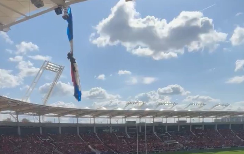 Parașutist prăbușit pe acoperișul stadionului se agață disperat în așteptarea salvatorilor