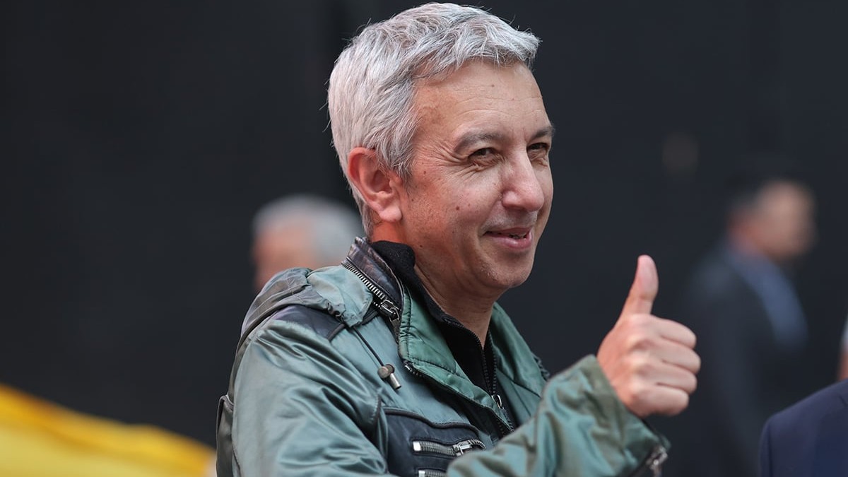 Dan Diaconescu îmbrăcat într-o haină verde -kaki arată cu degetul semnul ok.