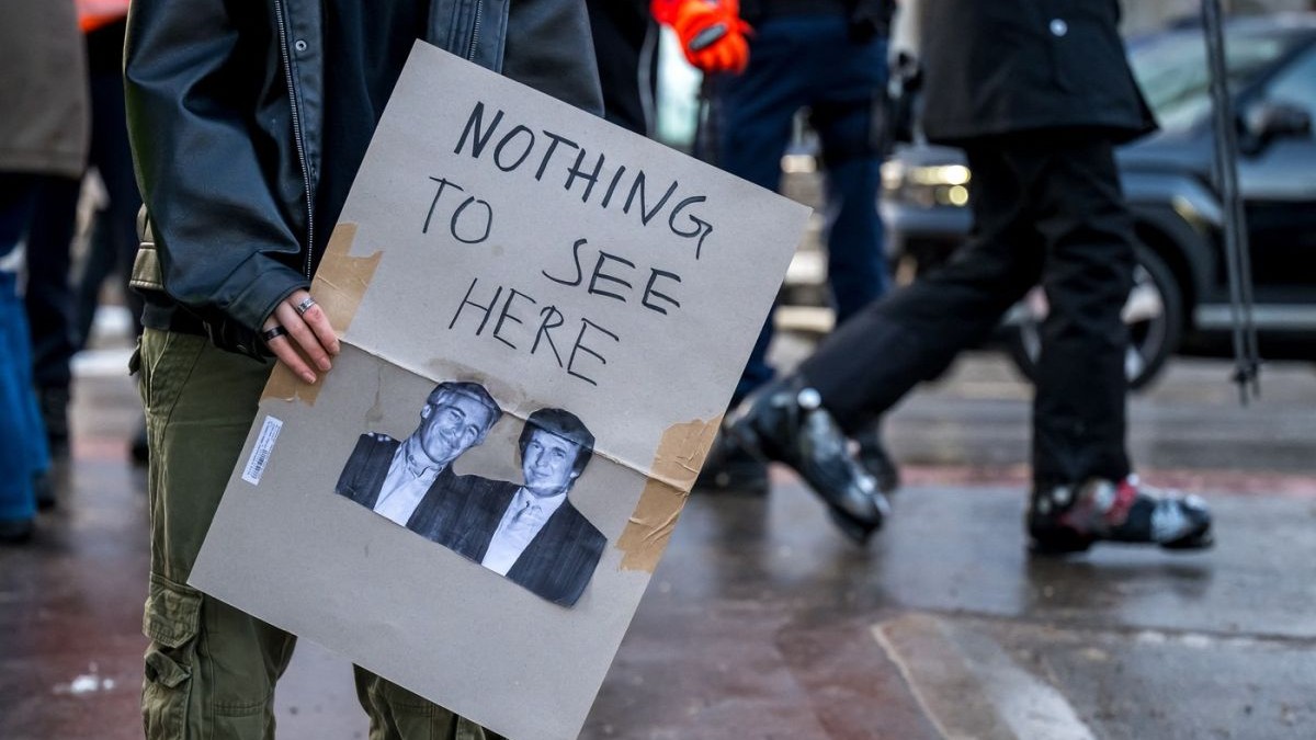 Un protestatar ține o pancartă cu fotografii care îi înfățișează pe Jeffrey Epstein și Donald Trump, 18 ianuarie 2026