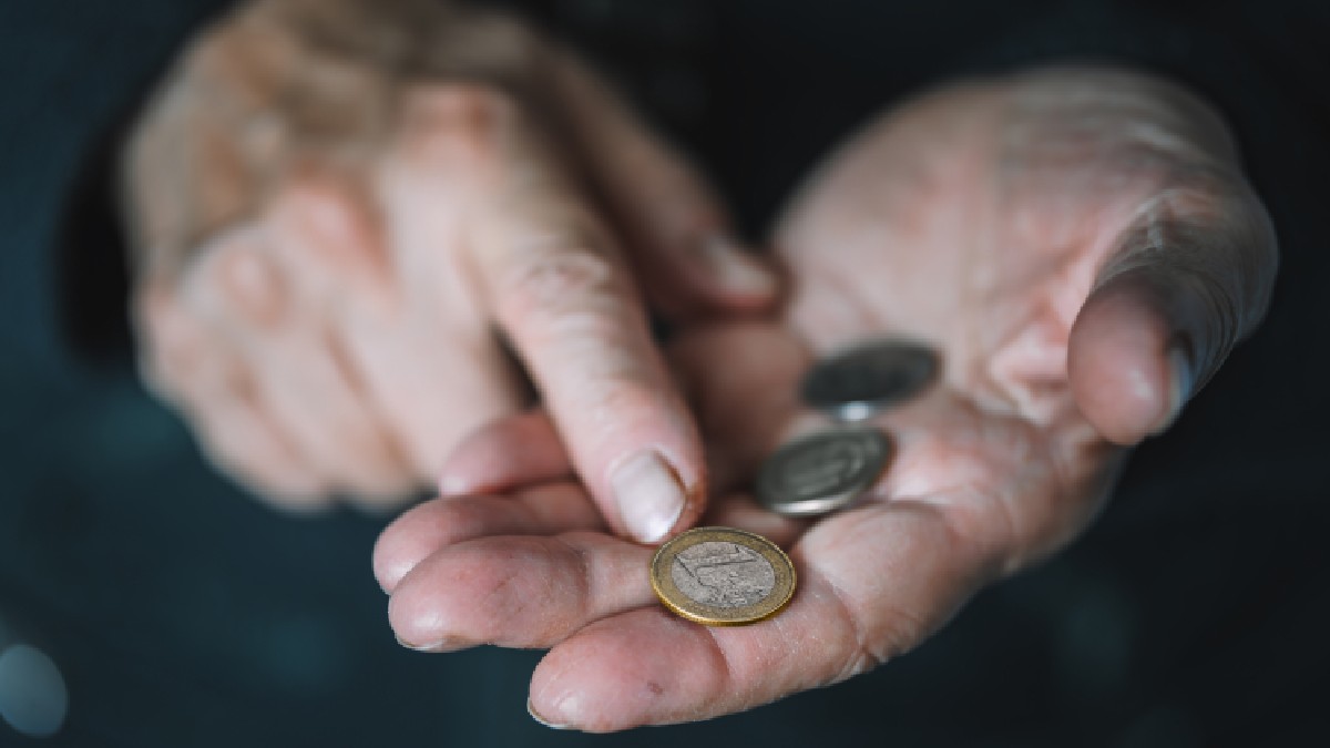 Un pensionar ține într-o mână trei monede euro, în timp ce le arată cu cealaltă mână