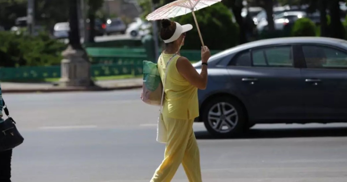 O femeie îmbrăcată în galben, care ține o umbrelă pe stradă