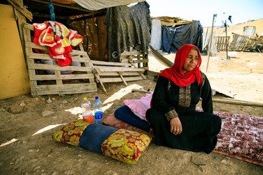 O femeie stă la umbră în fața casei sale din satul de beduini Khan al-Ahmar din West Bank