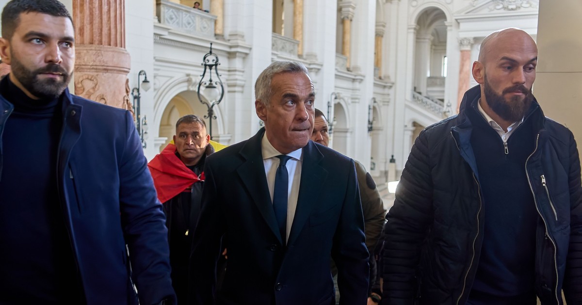 Fotografie cu Călin Georgescu, care este însoțit de doi bărbați.