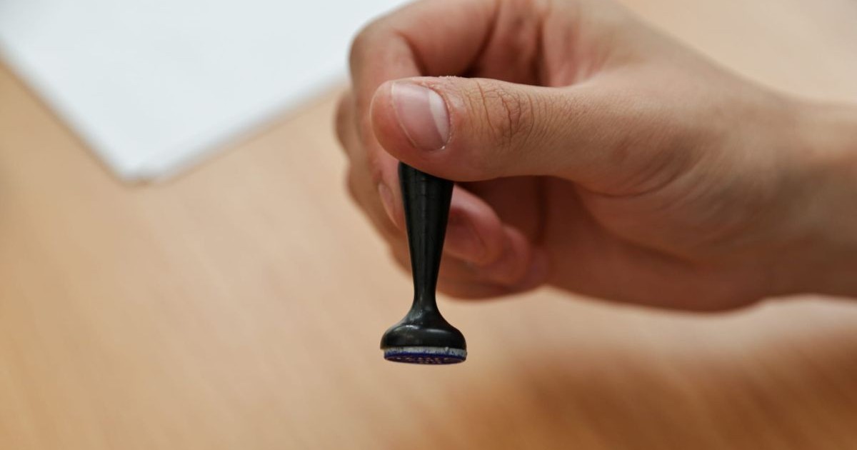 Un membru al unei secții de votare ține în mână o ștampilă și i -o dă unui alegător, la alegerile prezidențiale, 4 mai 2025