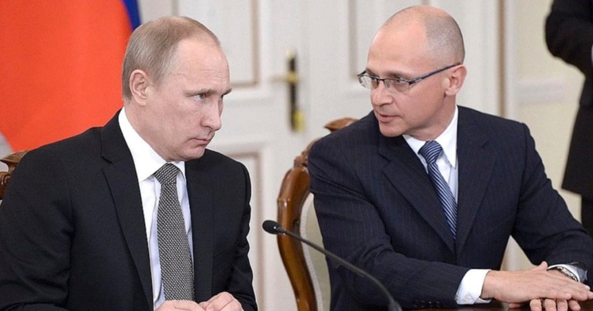 Vladimir Putin si Serghei Kirienko stau unul langa altul la o masa. Kirienko ii vorbeste lui Putin