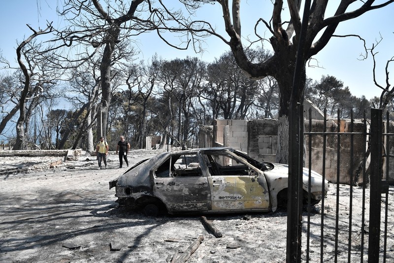 Locuitori din orașul Lambiri evaluează pagubele provocate de incendiu, pe 1 august | Foto: Profimedia