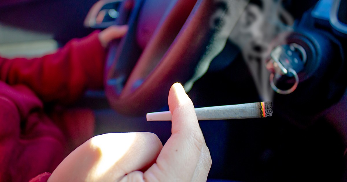 O persoană cu un joint de canabis fumând și conducând. Concept: conducere sub influența alcoolului, conducere sub influența alcoolului sau a drogurilor