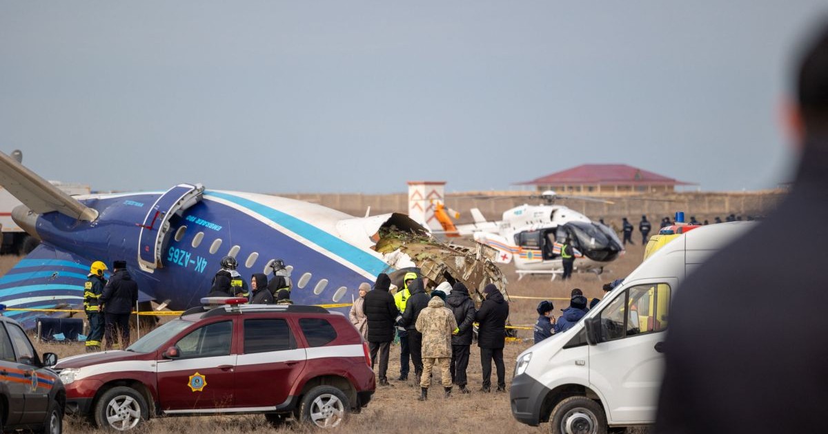 Un elicopter, o mașină de poliție și una de salvare sunt parcate lângă un avion prăbușit în apropierea orașului kazah Aktau, în timp ce mai multe persoane investighează incidentul, decembrie 2024