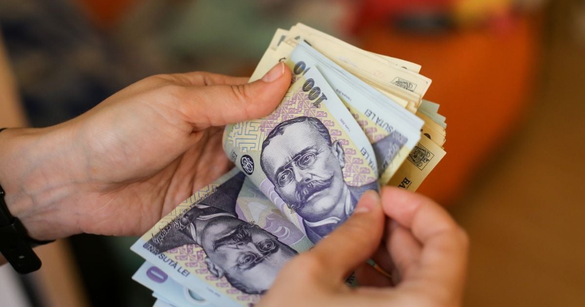 O femeie numără bani, în bancnote de 100 de lei și 50 de lei, pe fundal blurat