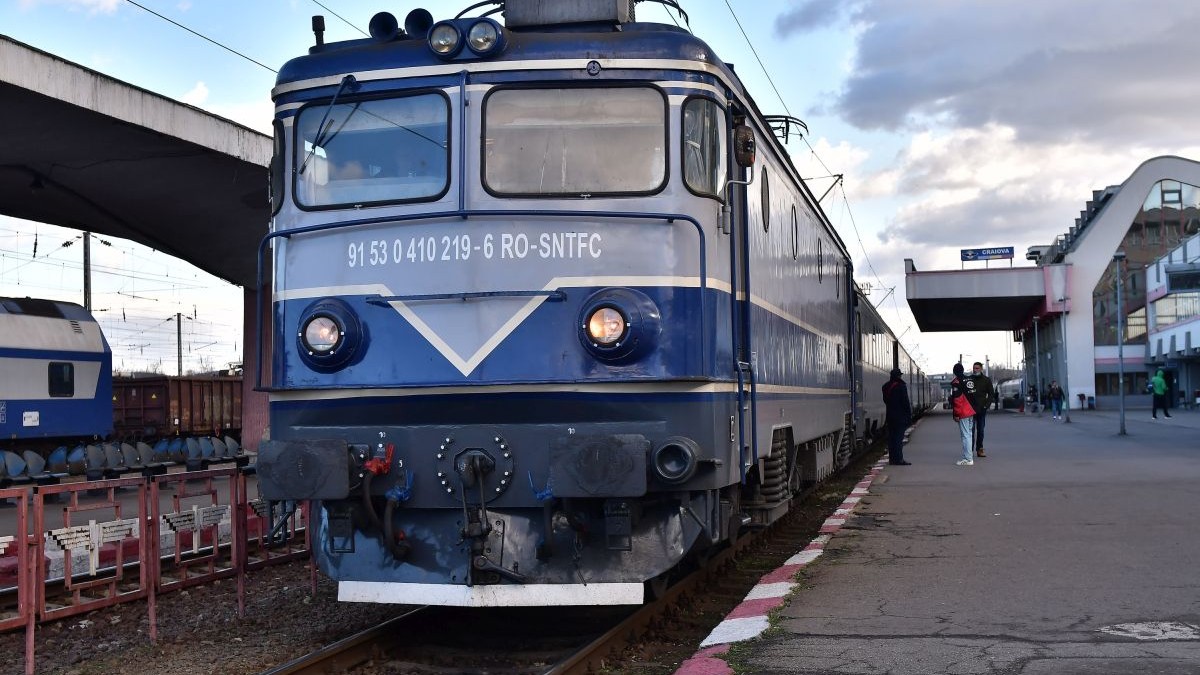 Un tren de călători staționează într-o gară