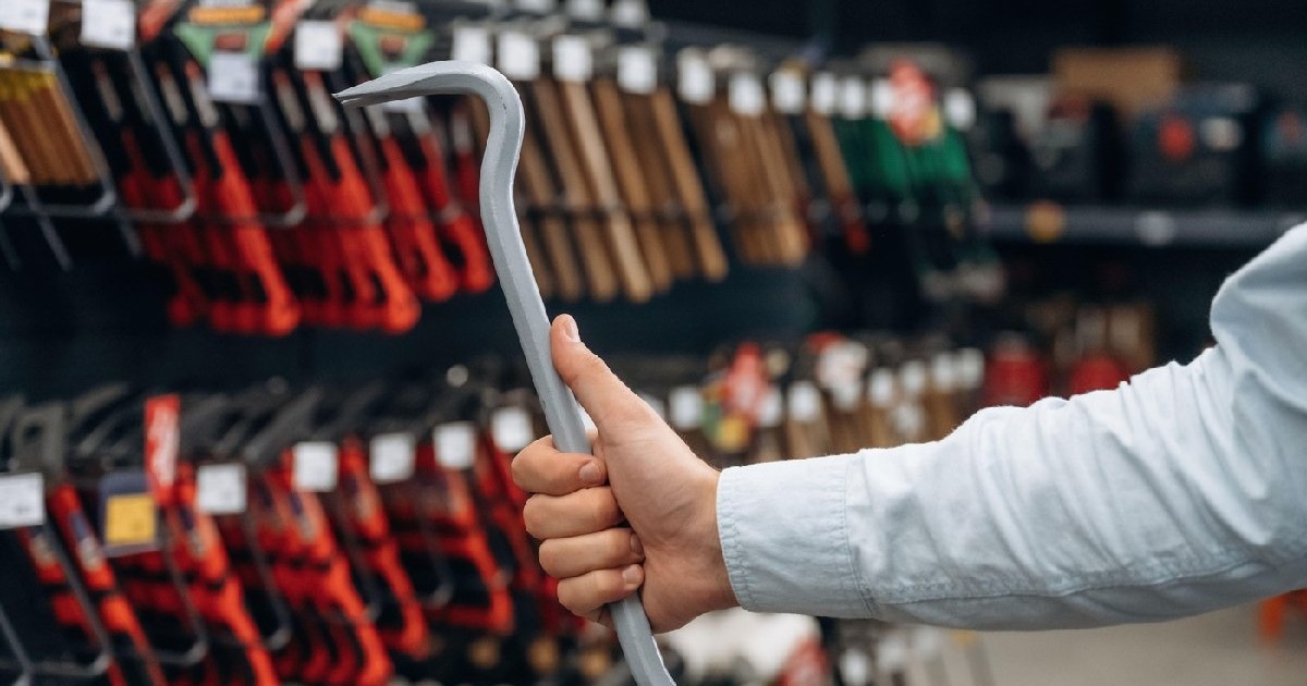 Un bărbat ține o rangă în mână, poartă o câmașă albă. Vedere detaliată de aproape a mâinii omului în magazinul de unelte