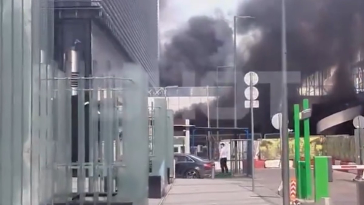 În imagine este ilustrată o parcare în care se observă fum negru, în urma unui incendiu