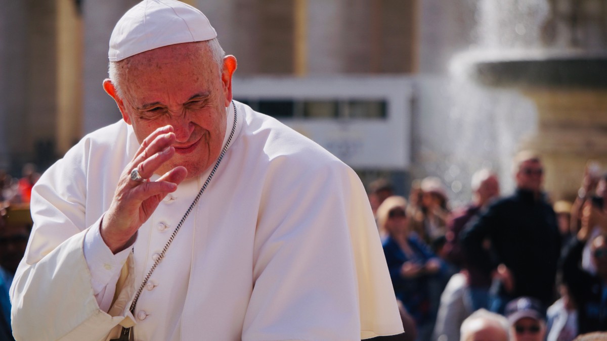 Papa Francisc, la Vatican, salutând mulțimea de oameni. Este îmbrăcat în haine specifice, albe, și are o cruce la gât.
