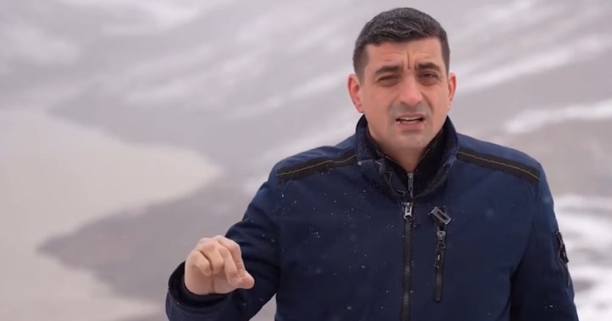 George Simion, îmbrăcat cu o haină de culoare albastru închis, pe marginea barajului Vidraru, în timp ce afară ninge