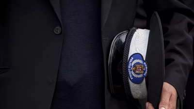 Un bărbat ține în mână o caschetă neagră de polițist