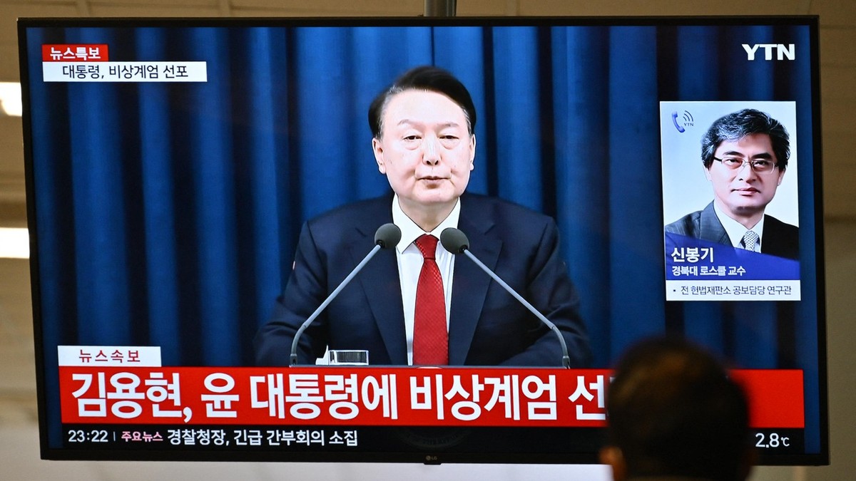 Un bărbat îl urmărește pe președintele Coreei de Sud, Yoon Suk Yeol, vorbind în timpul unei transmisiuni de știri la un televizor într-o gară din Seul, pe 3 decembrie 2024, după ce a declarat legea marțială de urgență