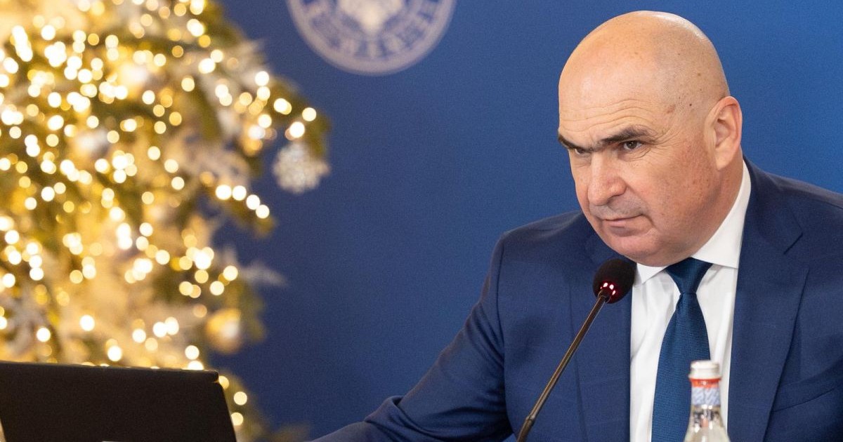 Ilie Bolojan este în fața unui laptop la o ședință de guvern, în timp ce pe fundal apare un brad împodobit de Crăciun, decembrie 2025