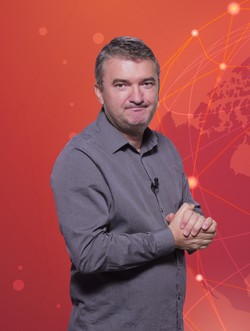 Dorin Chioțea, redactor șef Libertatea, îmbrăcat cu o cămașă gri, pe un fundal roșu