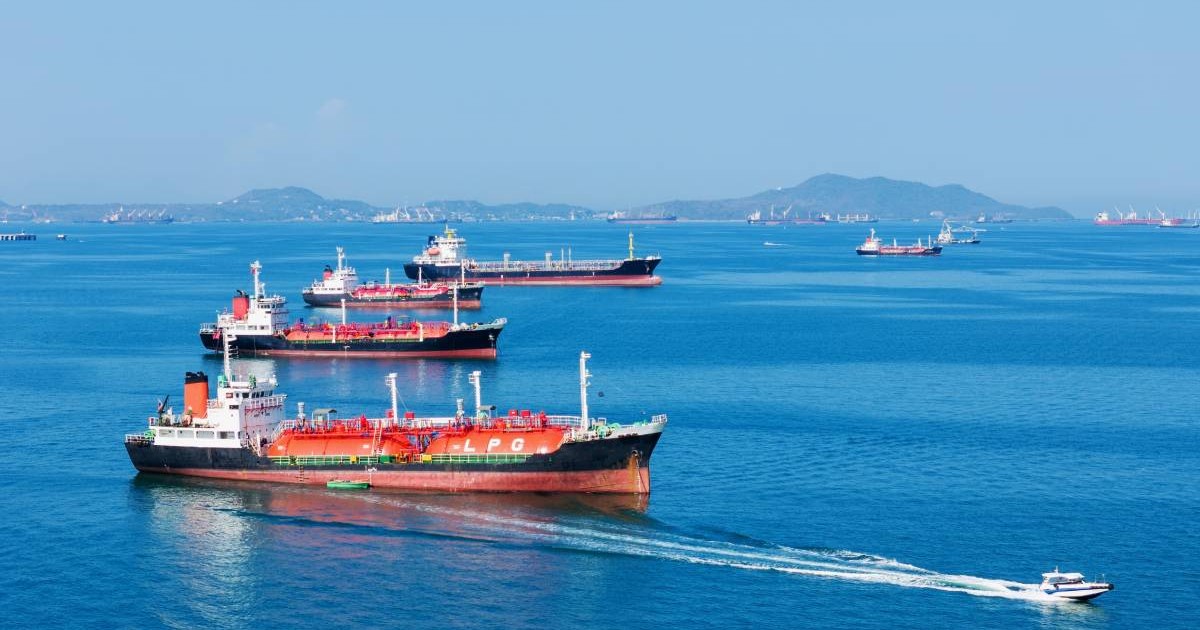 Nave-cisternă cu gaz și petrol GPL ancorate în ocean, cu o barcă de patrulare rapidă în prim-plan. Transportul energetic global, criza energetică de război și conceptul de blocadă din Strâmtoarea Ormuz
