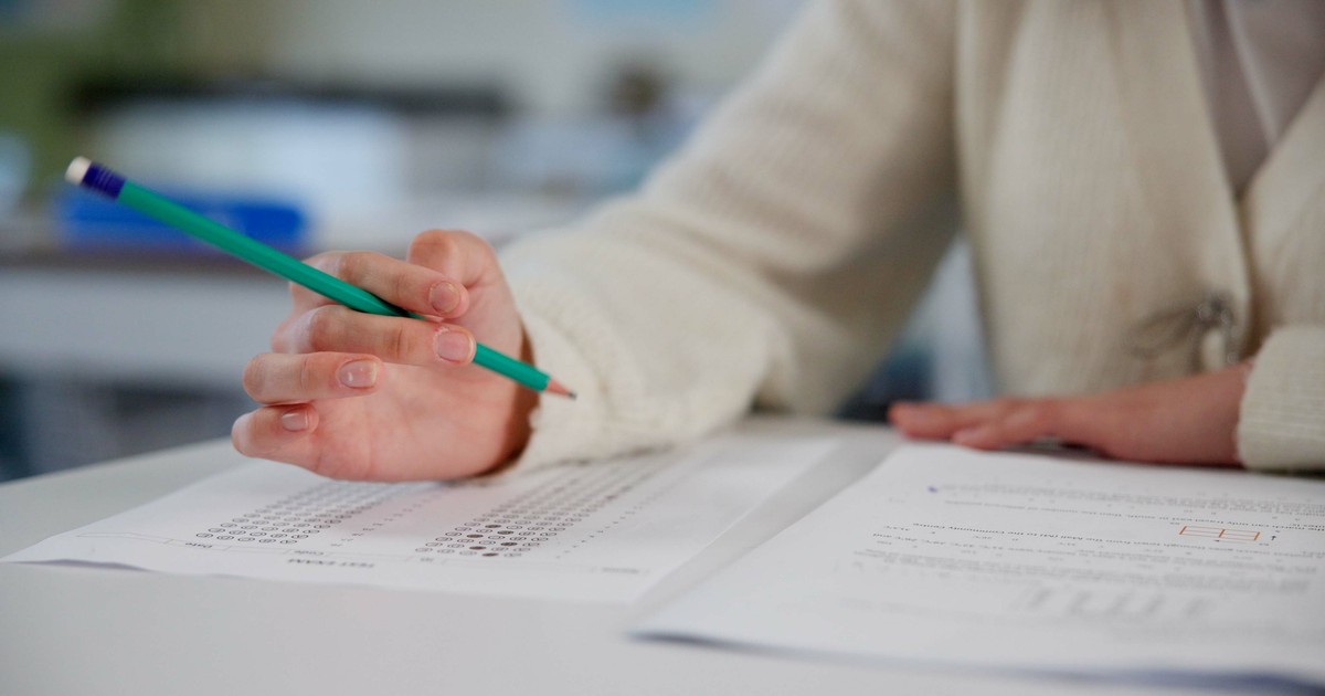 Elev care scrie cu creionul pe o foaie de hârtie la examen