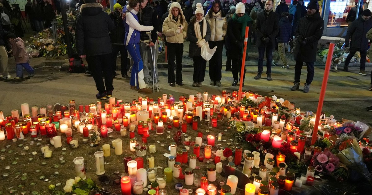 Oamenii aprind lumânări în apropierea barului Le Constellation, închis după incendiul devastator, în stațiunea Crans-Montana din Alpii Elvețieni