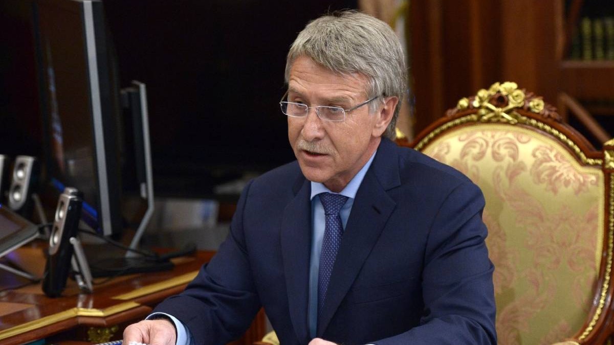 miliardarul rus Leonid Mikhelson CEO Novatek, asezat pe un scaun auriu, in costum inchis la culoare, cravata si camasa bleu, cu niste foi in mana, surprins in timp ce vorbeste
