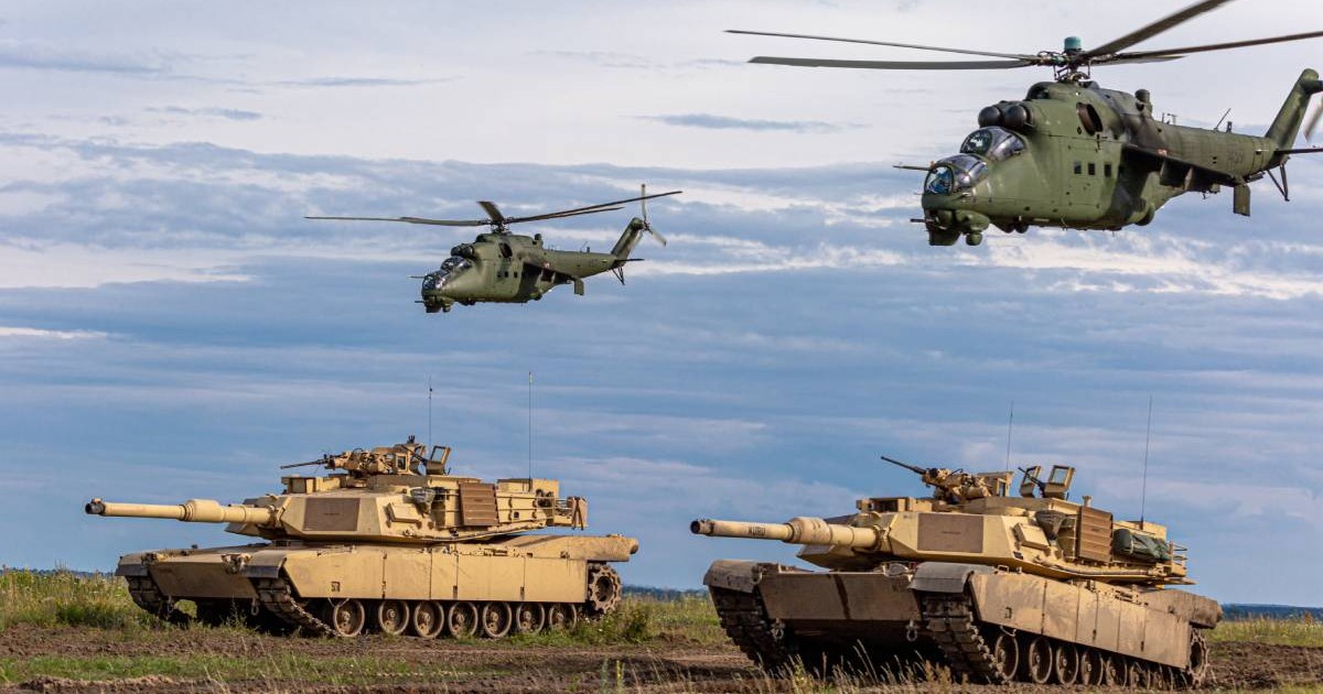 Tancuri Abrams pe un teren de luptă și elicoptere militare.
