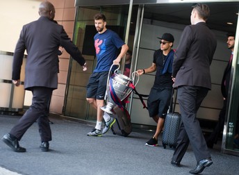 epa04787693 Gerard Pique (L) and Neymar (R) of FC Barcelona carry the UEFA Champions League trophy as they leave the Hotel Hyatt in Berlin, Germany, 07 June 2015. Barcelona clinched a fifth European champions title with a 3-1 victory over Juventus in the UEFA Champions League final in Berlin on 06 June 2015. EPA/GREGOR FISCHER