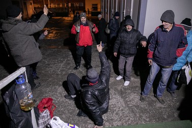 Câțiva dintre oamenii care așteaptă afară, la intrarea în adăpost, dansează pe ritmuri de manele ca să simtă că e Revelion, dar și pentru a se încălzi.