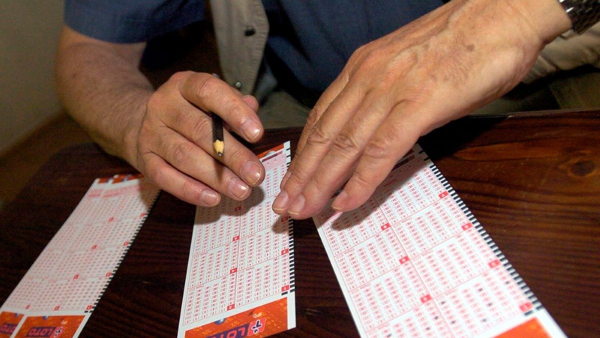 Un jucător de loto își pregătește biletele în agenție
