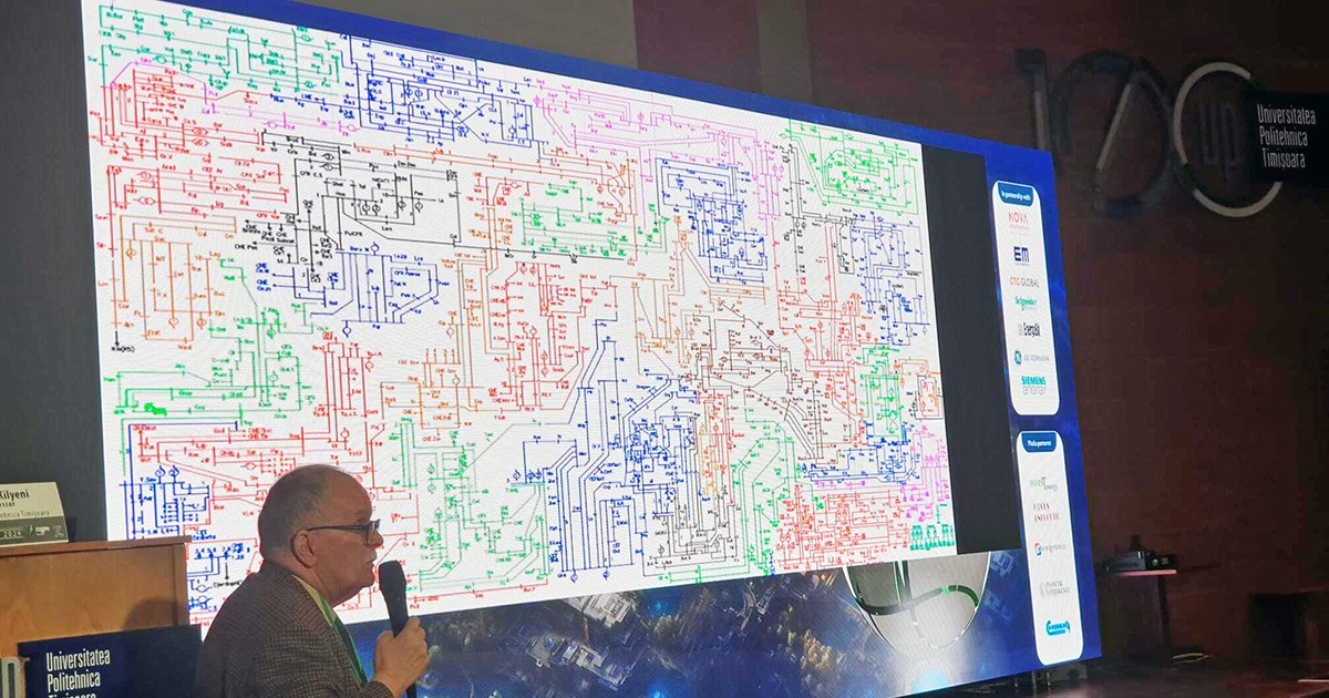 Un barbat cu un microfon in mana un fata unui panou cu electroni