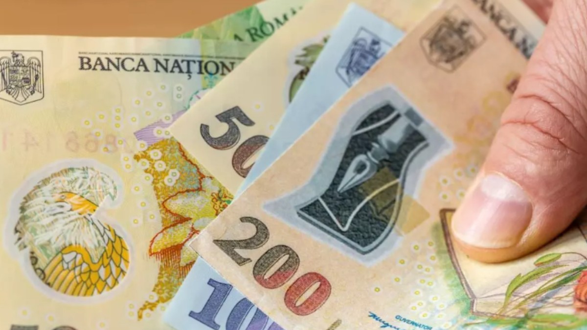 În imagine apar mai multe bancnote ținute de o persoană în mână