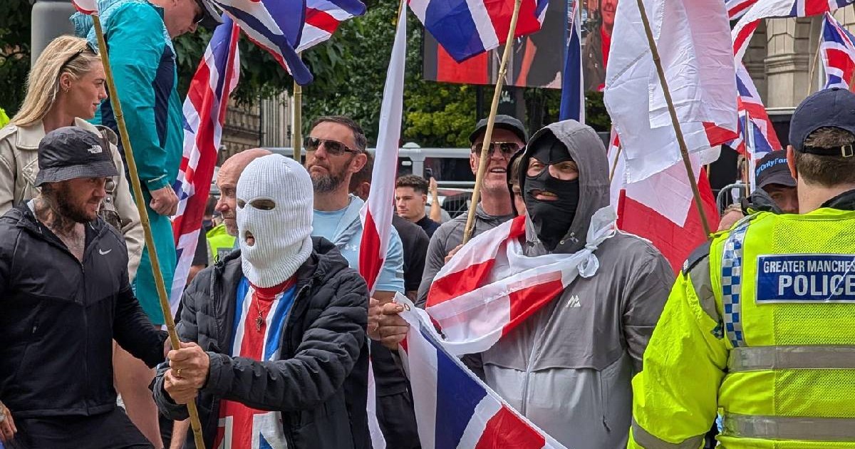Mai mulți protestatari anti-migranți din Anglia mascați și fluturând steaguri la o manifestație