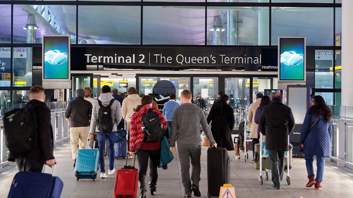 Mai multe persoane cară bagaje pentru a se îmbarca în aeroport